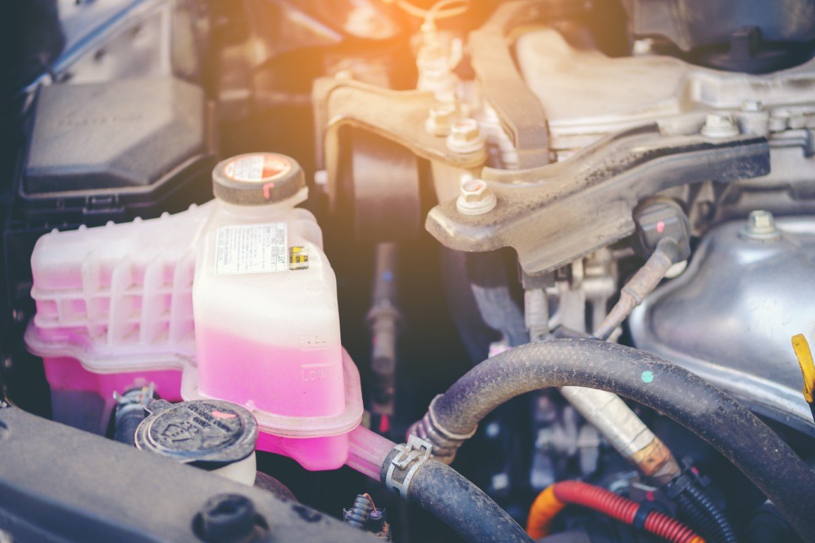 Coolant reservoir filled with pink antifreeze in an engine bay