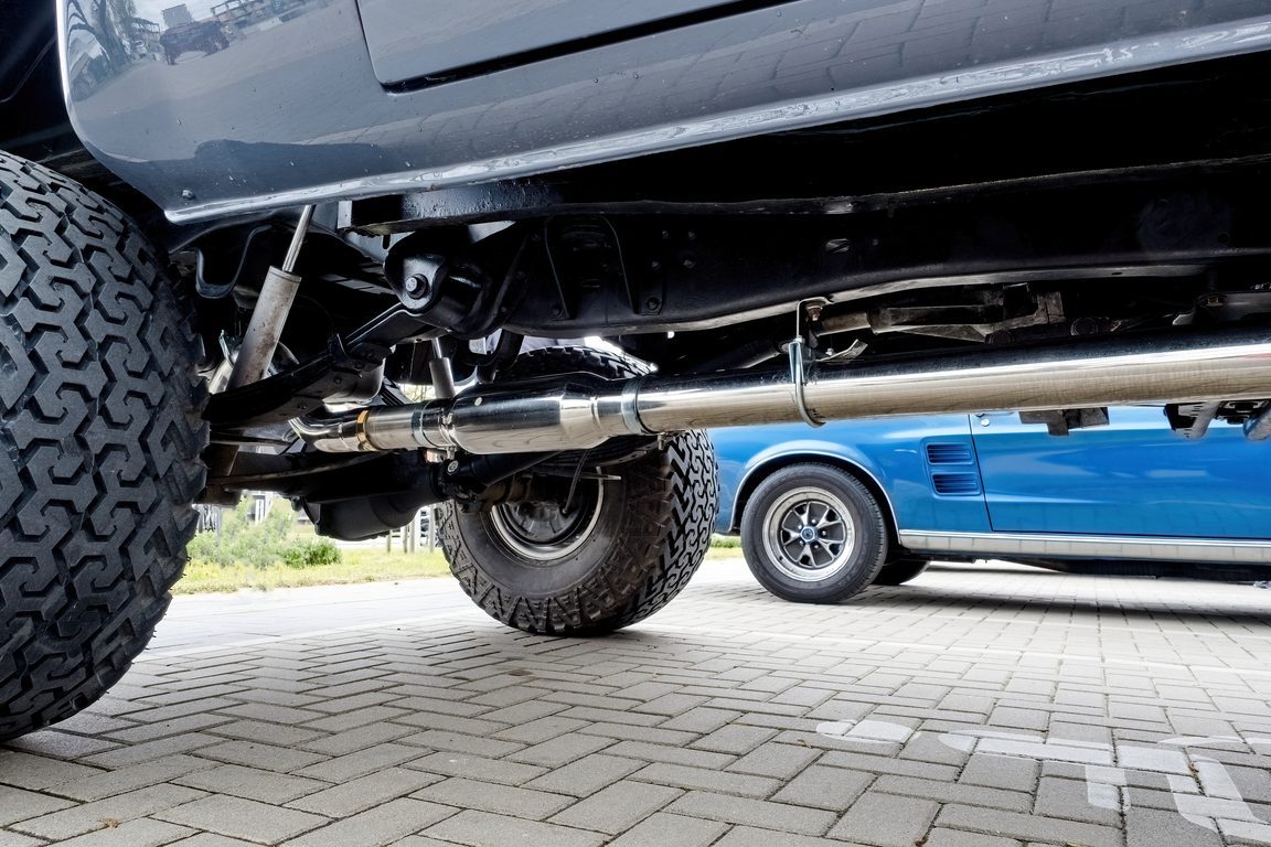 Underside of a raised truck showing the exhaust pipe running the length of the vehicle