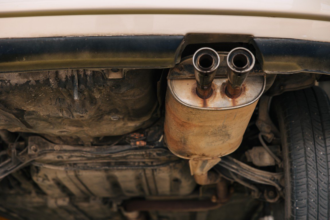 Rusted muffler and tailpipe seen from underneath a vehicle