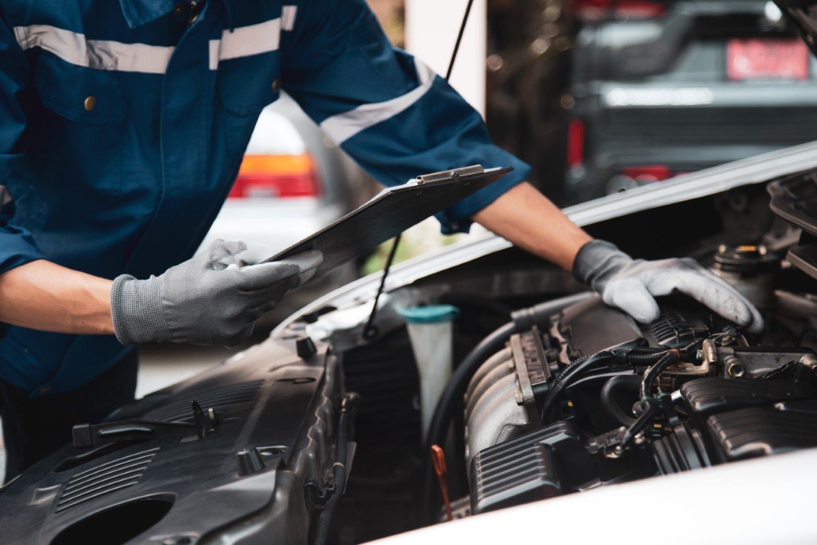 Technician checking an engine bay with an inspection clipboard