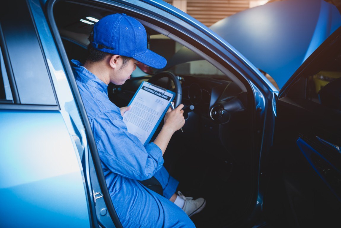 Technician with an inspection clipboard checking a vehicle at a shop