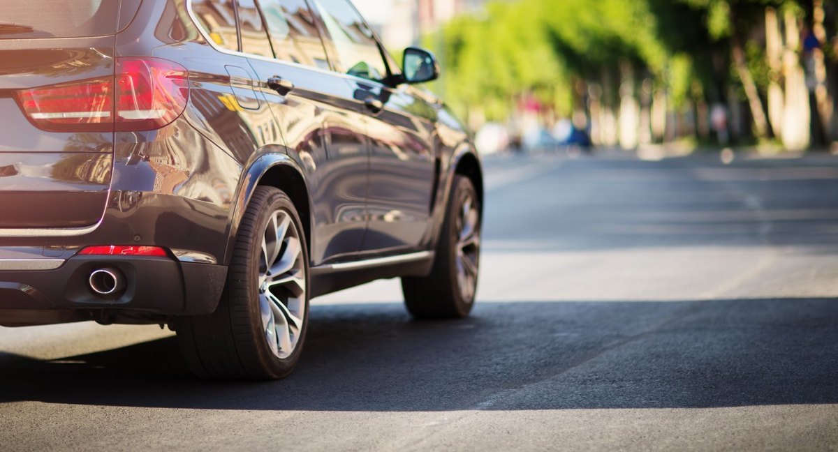 SUV driving away along a tree-lined street on a daily commute