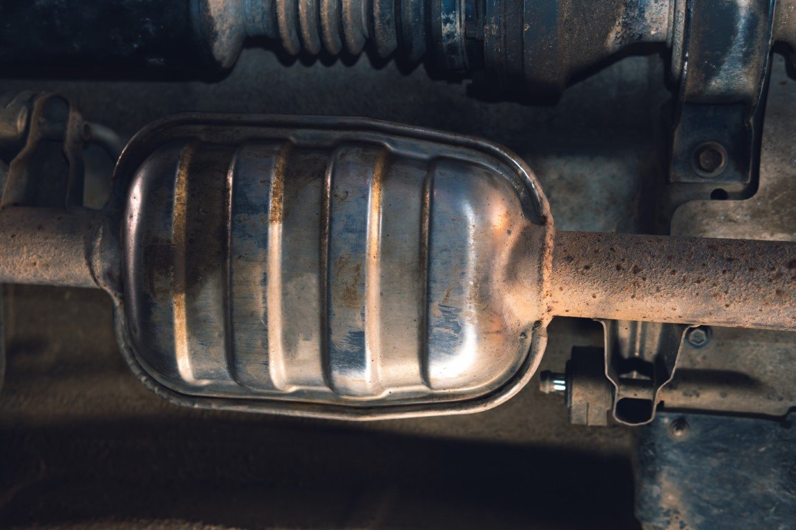 Worn and rusted muffler mounted underneath a vehicle